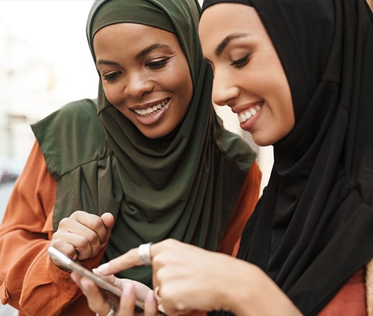 Two Muslim women looking at social media together